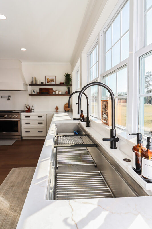White kitchen cabinets with large row of windows above.