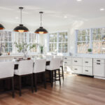 White perimeter kitchen cabinets with a dark stained island.
