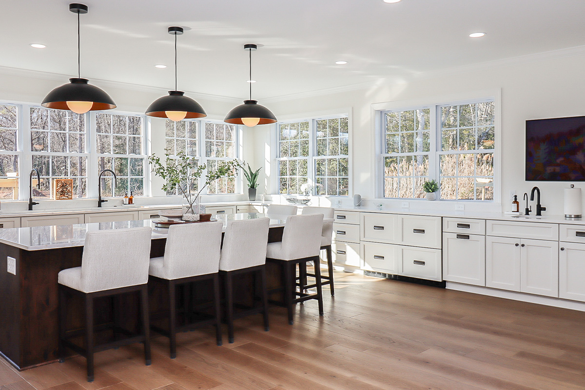 White perimeter kitchen cabinets with a dark stained island.