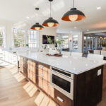 White perimeter kitchen cabinets with a dark stained island.