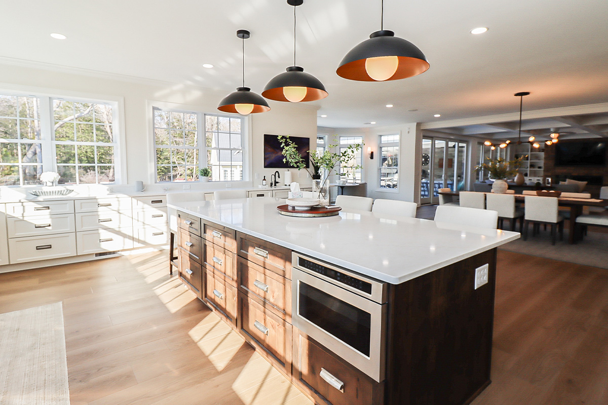 White perimeter kitchen cabinets with a dark stained island.