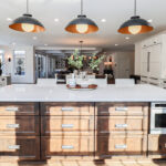 White perimeter kitchen cabinets with a dark stained island.