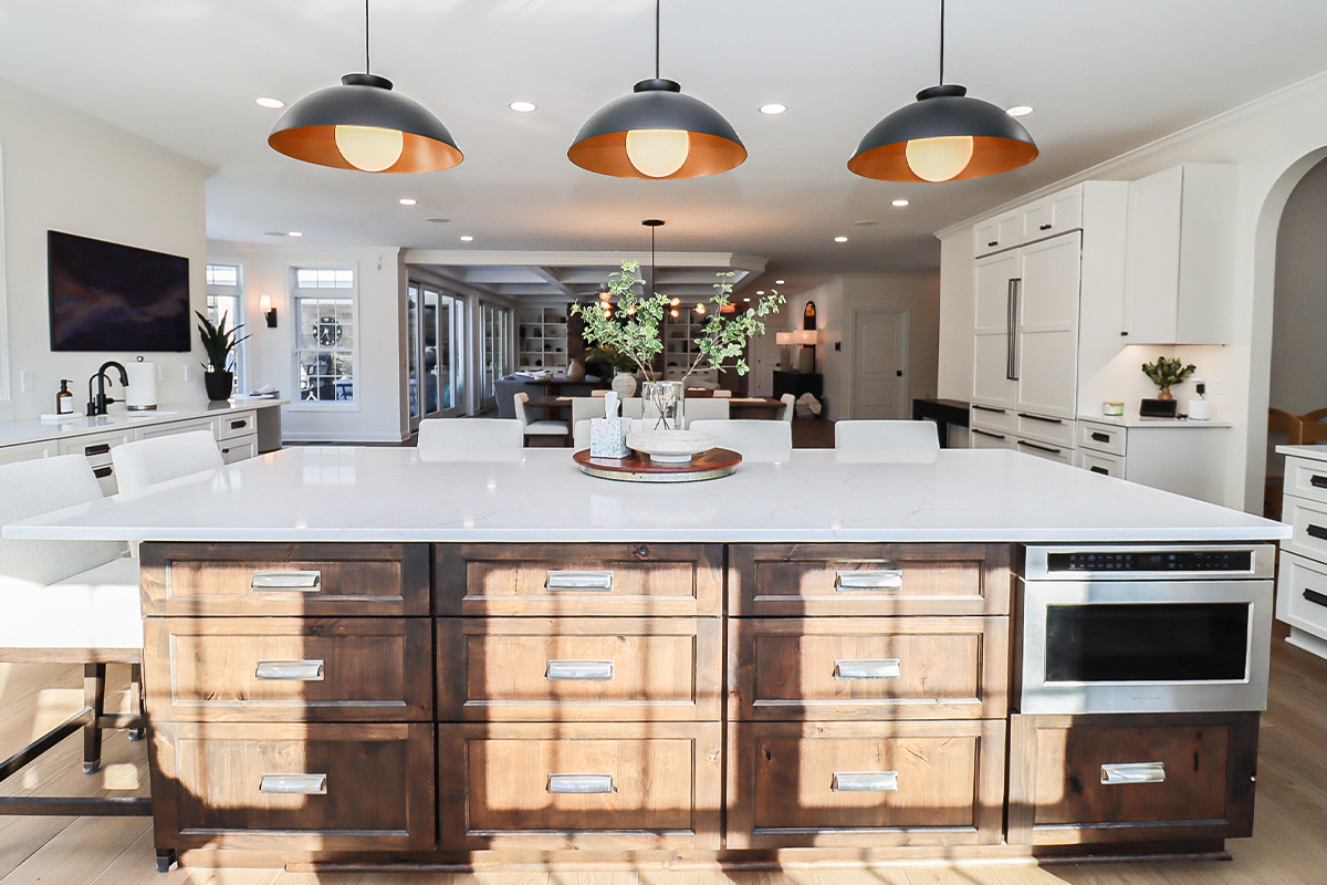White perimeter kitchen cabinets with a dark stained island.