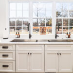 White kitchen cabinets with large row of windows above.