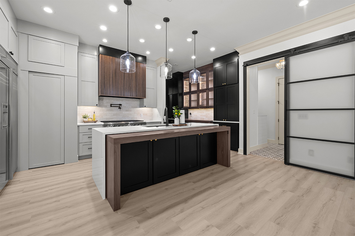 Light gray and black painted kitchen cabinets with walnut accent hutch cabinets, with a pullout walnut table connected to the island.