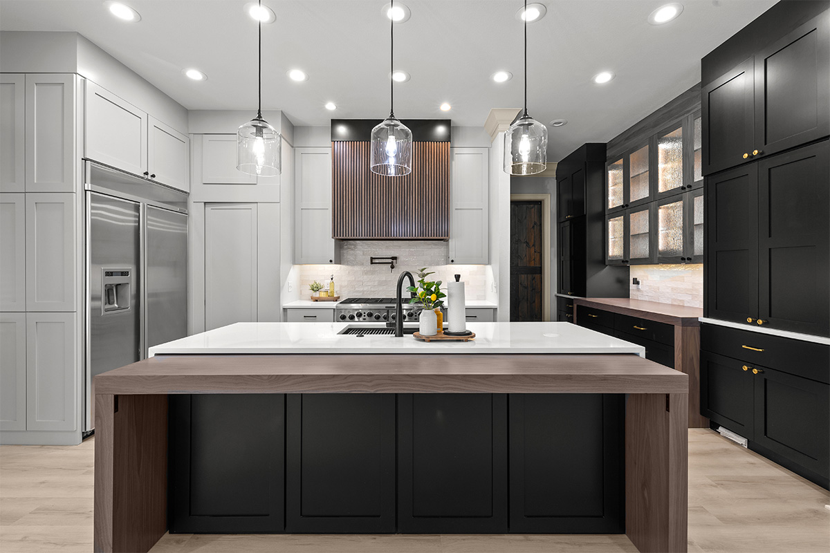 Light gray and black painted kitchen cabinets with walnut accent hutch cabinets, with a pullout walnut table connected to the island.