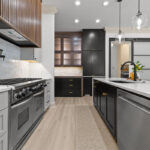 Light gray and black painted kitchen cabinets with walnut accent hutch cabinets, with a pullout walnut table connected to the island.