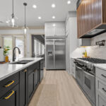 Light gray and black painted kitchen cabinets with walnut accent hutch cabinets, with a pullout walnut table connected to the island.