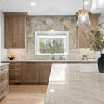 Light stained kitchen cabinets on stone wall.
