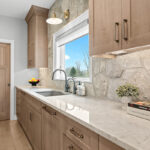 Light stained kitchen cabinets on stone wall.