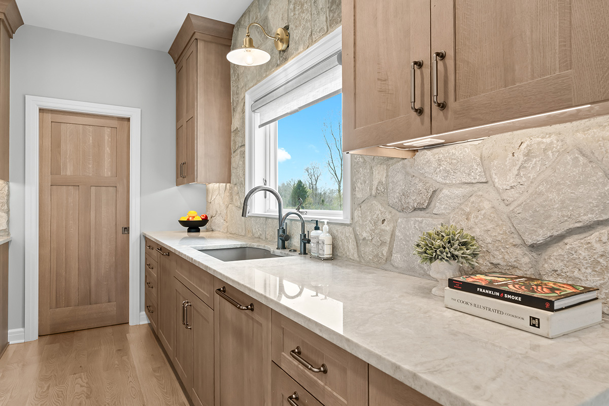 Light stained kitchen cabinets on stone wall.