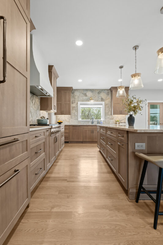 Light stained kitchen cabinets on stone wall.