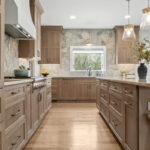 Light stained kitchen cabinets on stone wall.