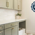 Light green mudroom cabinets with dog dish area under the counter.