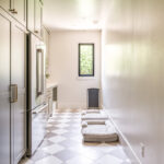 Light green mudroom cabinets with dog dish area under the counter and dog beds on the floor.
