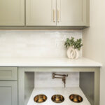 Light green mudroom cabinets with dog dish area under the counter.