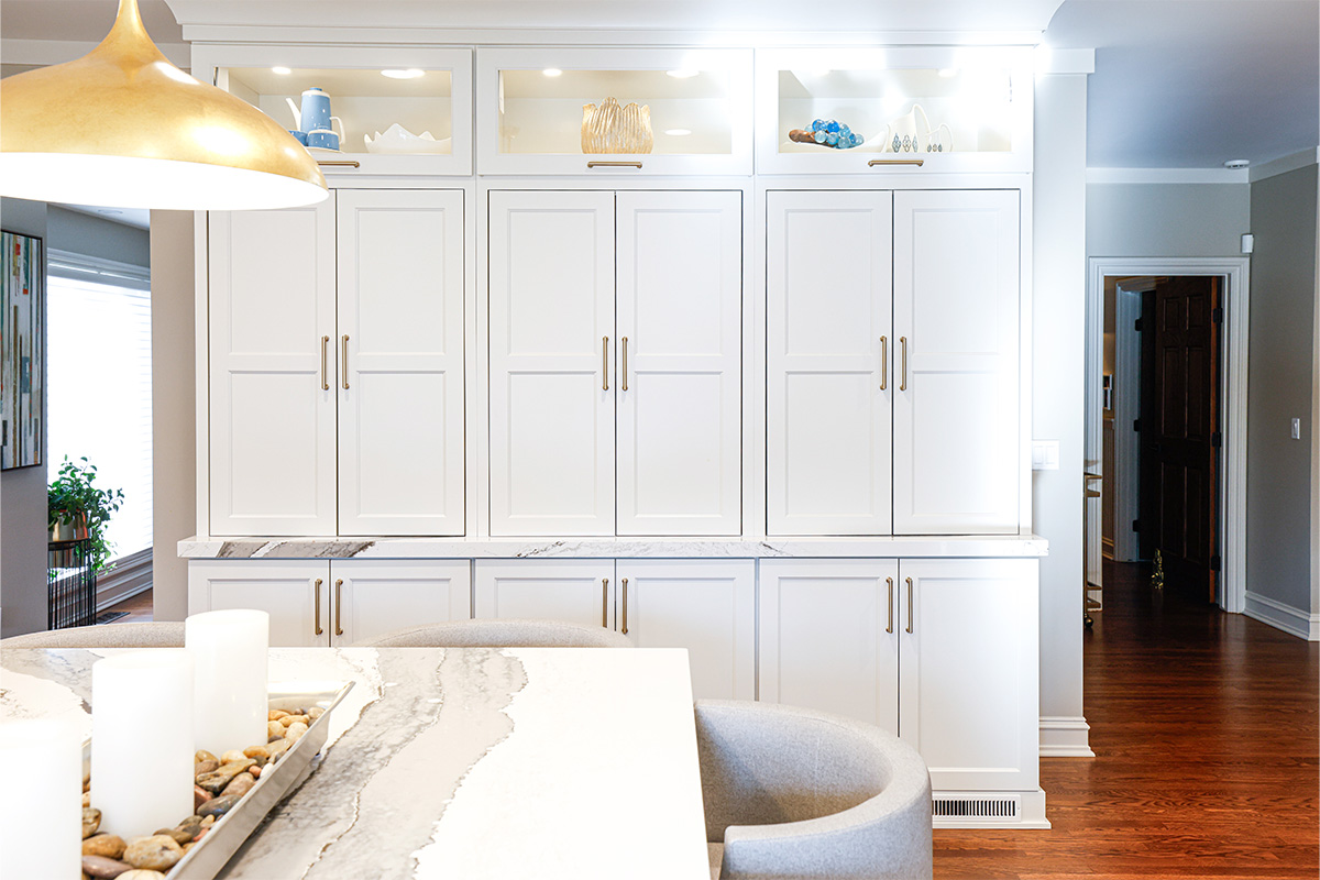 Tall white kitchen cabinets with glass top doors.