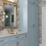 Light blue bathroom vanity cabinets with ornate gold mirrors and sink hardware.