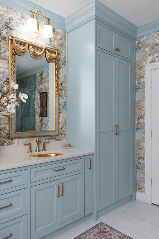 Light blue bathroom vanity cabinets with ornate gold mirrors and sink hardware.