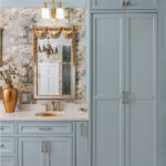 Light blue bathroom vanity cabinets with ornate gold mirrors and sink hardware.