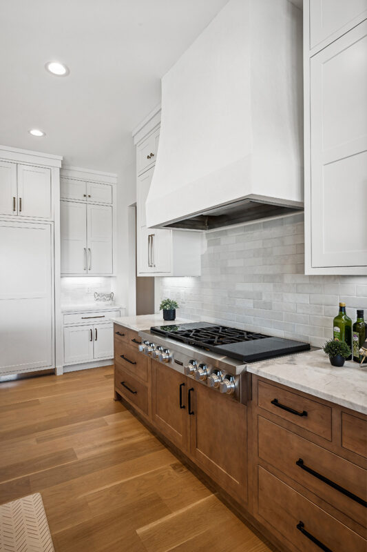 White painted and light brown stained kitchen with island.