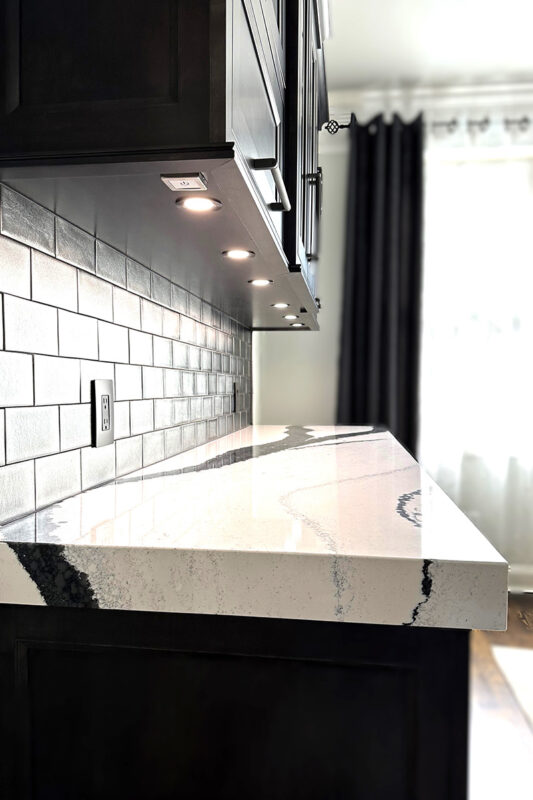 Dark stained bar cabinets with light marble counter and subway tile backsplash