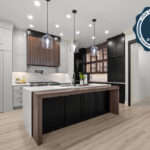 Light gray and black painted kitchen cabinets with walnut accent hutch cabinets, with a pullout walnut table connected to the island.