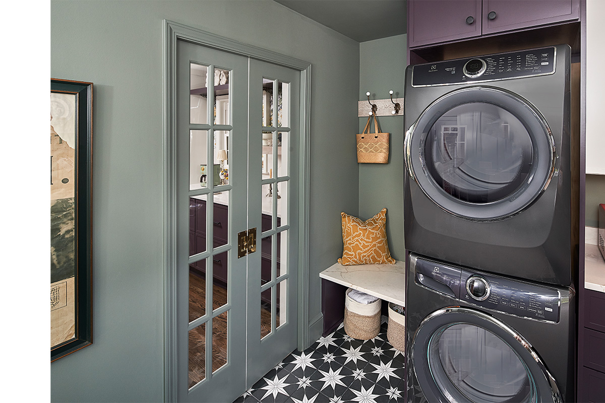 Purple stacked washer and dryer with stained wood floating shelves.