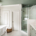Light green painted bathroom vanity and white standalone tub.