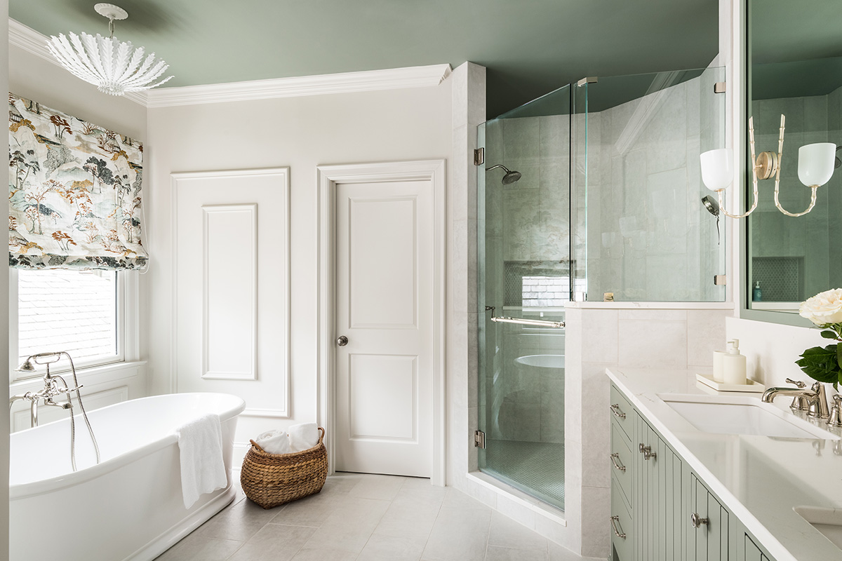 Light green painted bathroom vanity and white standalone tub.