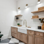 Light stained mudroom cabinets with farmer sink and floating shelves.
