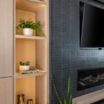 Dark brick fireplace with TV above and light stained cabinets on both sides.