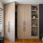 Dark brick fireplace with TV above and light stained cabinets on both sides.