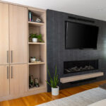 Dark brick fireplace with TV above and light stained cabinets on both sides.