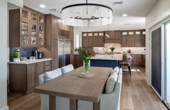Brown-stained kitchen cabinets and dining table with a blue pained island.
