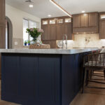 Brown-stained kitchen cabinets with a blue pained island.