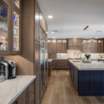 Brown-stained kitchen cabinets with a blue pained island.