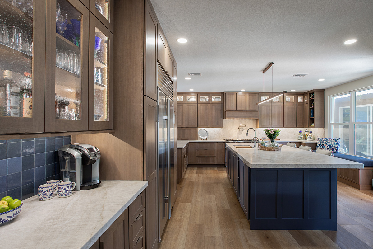 Brown-stained kitchen cabinets with a blue pained island.