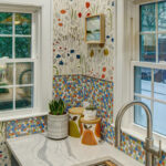 Blue kitchen cabinets with blue and yellow checkered floor and colorful backsplash.