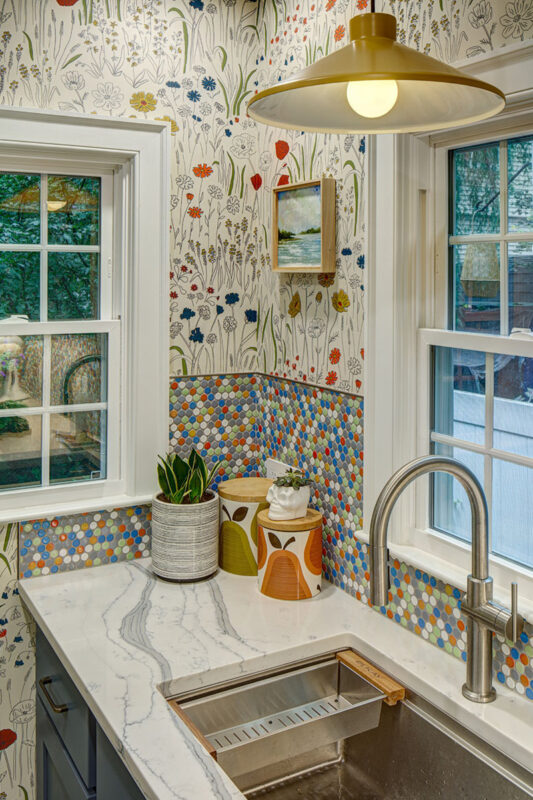 Blue kitchen cabinets with blue and yellow checkered floor and colorful backsplash.