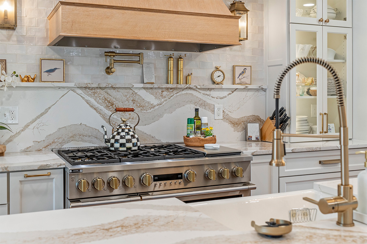 White kitchen with marble counter tops and backsplash with stained wood hood.