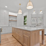 White kitchen perimeter cabinets with an island in washed out light brown Vita stain on Rift White Oak.