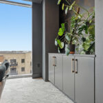 Gray cabinets with plant on the counter near a large window.