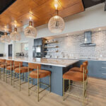 Gray painted office breakroom kitchen with long island with many seats.