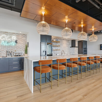 Gray painted office breakroom kitchen with long island with many seats.