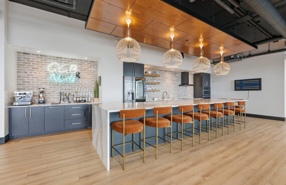 Gray painted office breakroom kitchen with long island with many seats.
