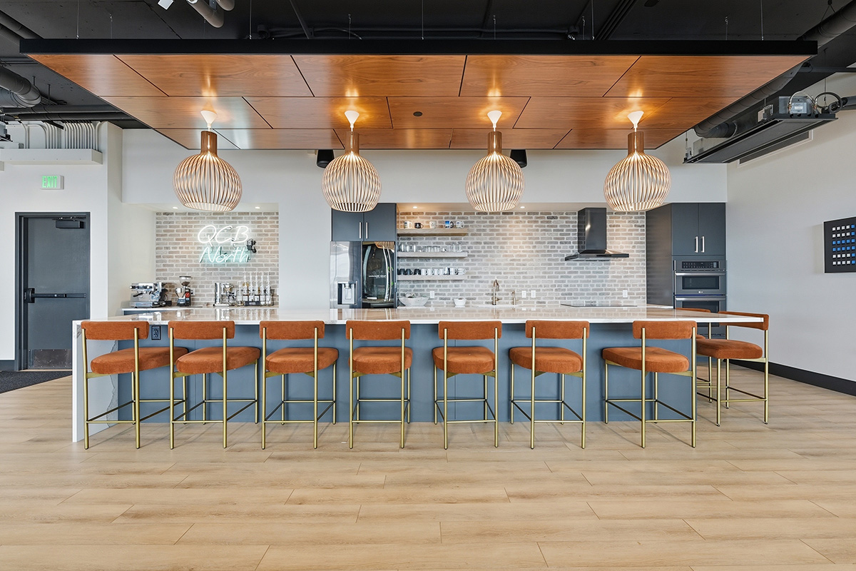 Gray painted office breakroom kitchen with long island with many seats.