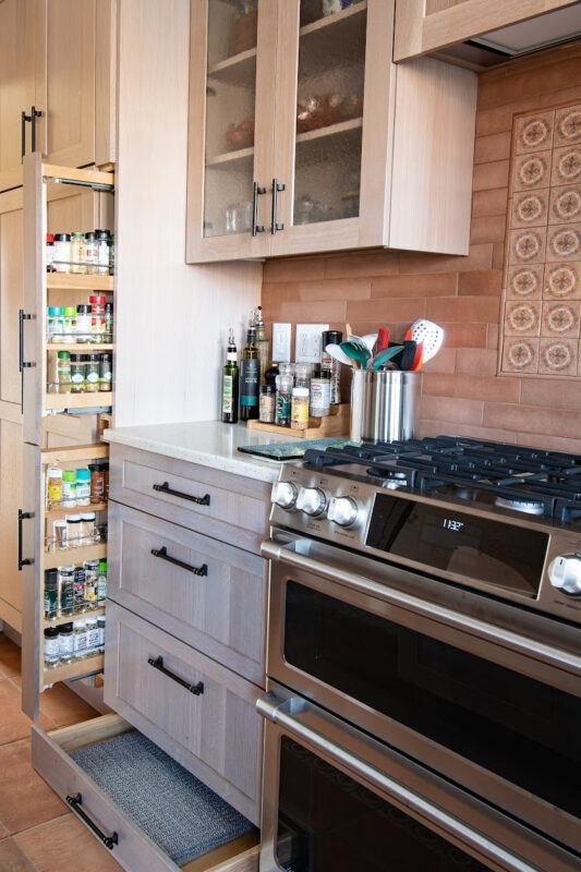 Quartersawn White Oak kitchen in a light Pampas finish showing a pulled out spice storage kits.