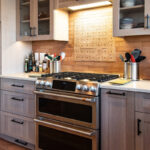 Quartersawn White Oak kitchen in a light Pampas finish with small island and stainless steel appliances.