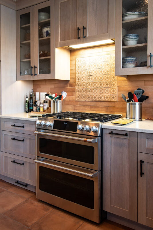 Quartersawn White Oak kitchen in a light Pampas finish with small island and stainless steel appliances.